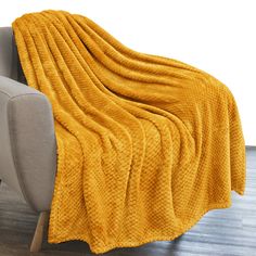 a couch with a yellow blanket on top of it and a chair in the background