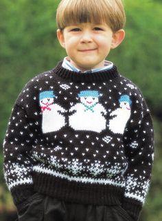 a young boy wearing a black and white sweater with snowmen on it, smiling at the camera