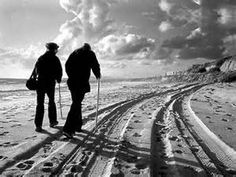 two people walking on the beach with skis