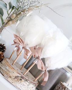 three wooden sticks with bows tied to them on top of a white mantle next to a pine cone