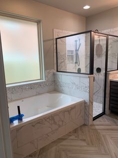 a bathroom with a large tub and walk in shower next to a window on the wall