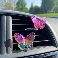 two colorful butterflies sitting on the dashboard of a car