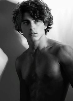 a shirtless young man poses for a black and white photo