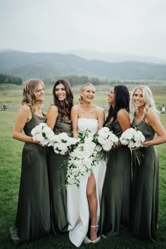 a group of women standing next to each other on top of a lush green field