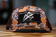 From the high plains of the South Platte to the City Streets of Denver, Colorado.  These hats perform great in all conditions! Available now in Lake Camo and Pebble. More color options are in the works! Let us know if you suggestions and we will be open to accommodate you. Complete the look with one of our Rocky Mountain Waterfowl hoodies! This hat would make a perfect valentines day gift for the man or woman in your life who loves to waterfowl hunt! #rockymountainwaterfowl #westernwaterfowl #goosehunting #duckhunting #rockymountains Brown Western Style Baseball Cap For Outdoor, Military Hat With Flat Bill For Outdoor Activities, Military Flat Bill Hat For Outdoor Activities, Brown Western Snapback Hat For Outdoor, Country Style Brown Baseball Cap For Outdoor, Outdoor Camouflage Baseball Cap, Military Hunting Hat With Curved Brim, Curved Brim Military Hat For Hunting, Military Style Hunting Hat With Curved Brim