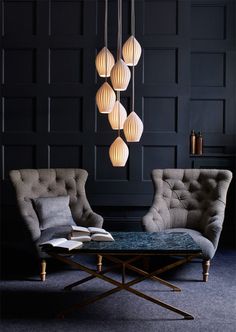 a living room with chairs and lamps hanging from it's ceiling over a table