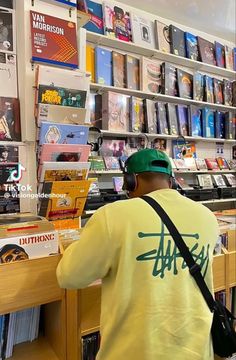 a man standing in front of a bookshelf with headphones on his ears