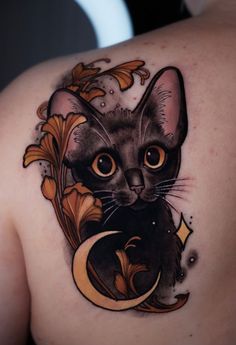 a cat tattoo on the back of a woman's shoulder, with an ornamental design