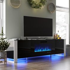 a living room with a large television and blue flames on the fireplace in front of it