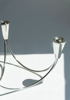 two metal candlesticks sitting on top of a white table