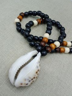 The large Cowrie shell necklace is approximately 26 inches long. the shell is approximately 3 inches long and 2 inches wide. It is beaded with black, brown and off white beads. If you have any questions please feel free to contact us at anytime. All shipping options are available. All items will be shipped out Monday through Friday. Receipts will be emailed out for immediate access. All items will be shipped out carefully and every shipment can be made with extra insurance upon request. All othe Black Necklaces With Large Beads For Beach, Black Beaded Necklace For Vacation, Brown Beaded Shell Necklace For Beach, Brown Beaded Shell Necklace For The Beach, Brown Shell Necklace For Vacation, Beaded Brown Shell Necklace For Beach, Brown Shell Necklace For Beach, Brown Necklaces With Black Beads For Beach, Shell Necklace With Wooden Beads For Beach