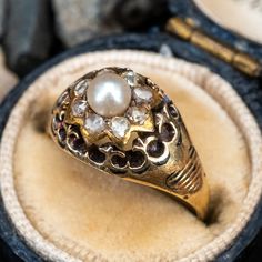 This charming late Victorian era ring is centered with a post set, natural pearl. The center is surrounded by eight (8) bead set, rose cut diamonds accented with taille d'epargne details. The ring measures 9.8mm at the top, rises 6.5mm above the finger, tapering to 1.1mm wide and 0.5mm thick at the base of the shank. The ring is currently a size 4 and shows moderate overall wear. We left the ring unpolished with a lovely patina finish. Heirloom Pearl Ring With Rose Cut Diamonds For Anniversary, Heirloom Pearl Ring With Diamond Accents, Heirloom Oval Pearl Ring With Rose Cut Diamonds, Antique Pearl Ring For Wedding, Heirloom Pearl Ring With Rose Cut Diamonds For Gift, Heirloom Oval Pearl Ring, Antique 14k Stamped Pearl Ring For Wedding, Vintage Oval Diamond Pearl Ring, Antique 14k Stamped Pearl Wedding Ring