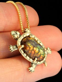 "\"Sylvester Tortoise\" Pendant is a one of a kind design cast in 18K gold. A 5 carat Fire Agate is the shell for this miniature tortoise pendant. The green, orange and gold iridescence of the fire agate makes a plate like pattern, reminiscent to the plates on a turtle or tortoise shell and the bottom of the shell is carefully etched with the plate pattern. The Tortoise is 1\" long and 5/8\" across.   The stone is 9/16\" high X 3/8\" across.   All Marty Magic Jewelry is packaged in a beautiful box, embossed with the gold foil Marty Magic dragon logo. Perfect for any occasion! Designed in Santa Cruz California by Marty Magic.  Made in the U.S.A." Luxury Collectible Bronze Jewelry, Handmade 14k Gold Oval Cabochon Jewelry, Collectible Yellow Gold Necklaces With Gemstone, Unique Polished Yellow Gold Jewelry, Unique Yellow Gold Collectible Jewelry, Unique Yellow Gold Necklace With Cabochon, Luxury Polished Bronze Jewelry, Collectible 14k Gold Gemstone Necklace, Collectible Yellow Gold Jewelry With Oval Cabochon