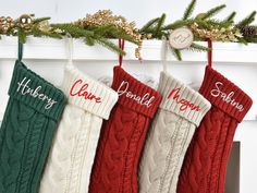 three christmas stockings hanging from a mantel decorated with pine cones and evergreen needles, along with personalized names on them