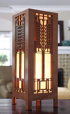 a wooden table lamp sitting on top of a hard wood floor next to a couch