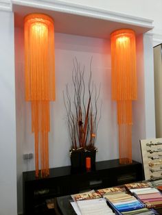 a room with two tall orange lamps and some books