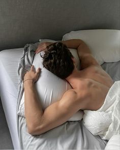 a shirtless man laying in bed with his head on the pillow as he sleeps