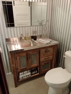 a white toilet sitting next to a wooden sink vanity in a bathroom under a mirror