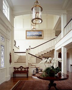 an elegant entry way with white flowers on the table and stairs leading up to the second floor