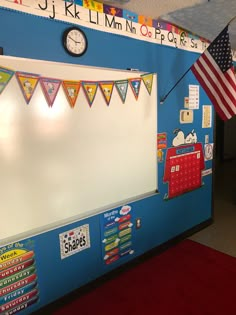 a bulletin board with flags hanging from it's sides and a clock on the wall