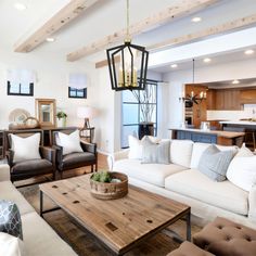 a living room filled with white furniture and lots of wood beams on the ceiling above