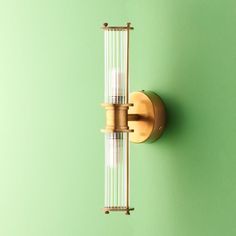 a wall mounted light on the side of a green wall with two glass tubes attached to it