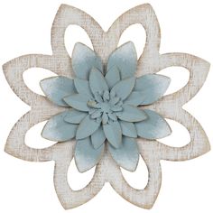 a white and blue flower is hanging on a wooden wall ornament in the shape of a flower