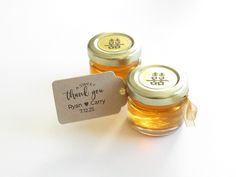 two honey jars with labels on them sitting next to each other, one is filled with honey and the other has a label that says thank you