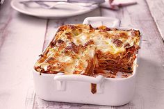 a casserole dish with meat and cheese in it sitting on a wooden table