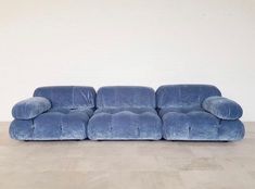 a blue couch sitting on top of a hard wood floor next to a white wall