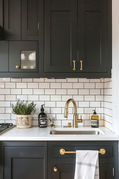 a kitchen with black cabinets and white subway tile backsplash, gold handles, brass accents