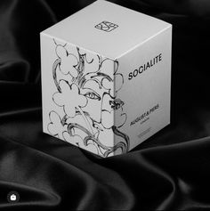 a white box sitting on top of a black satin covered table cloth with the word socialite printed on it