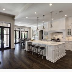 a large open kitchen with white cabinets and wood flooring is pictured in this image