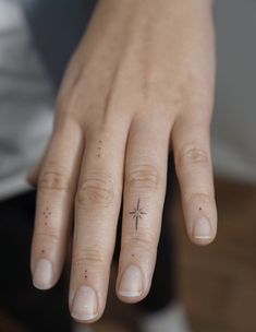 a woman's hand with a tiny star tattoo on it