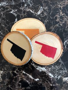 three wooden plates with different designs on them sitting on a marble counter top next to each other