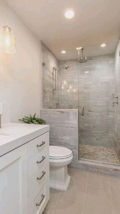 a bathroom with a walk in shower next to a white toilet and sink under lights