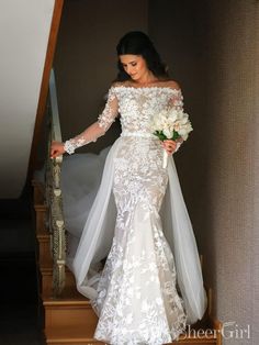 a woman in a wedding dress is walking down the stairs with her bouquet on her hand