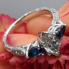 a diamond and blue sapphire ring sitting on top of a flower