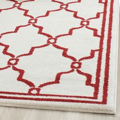 a white rug with red trimmings on the edges and a light wood floor