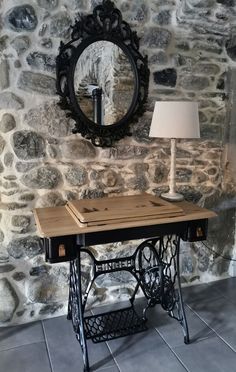 an old sewing machine sits in front of a stone wall with a mirror on it