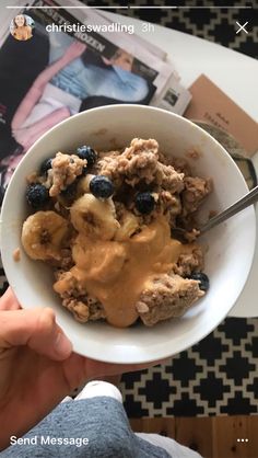 a person holding a bowl of cereal with bananas and blueberries