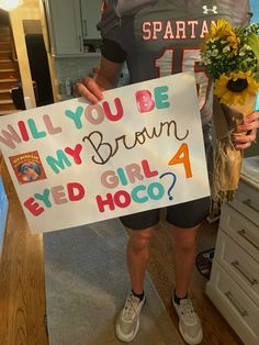 a woman holding a sign that says will you be my brown eyed hoo?