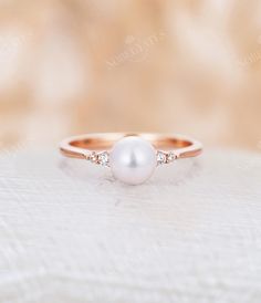 a pearl and diamond ring sitting on top of a white cloth