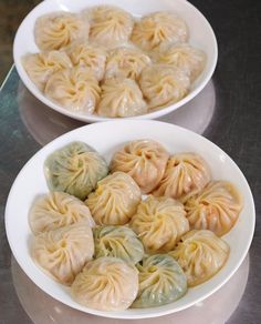 two white bowls filled with dumplings on top of a table