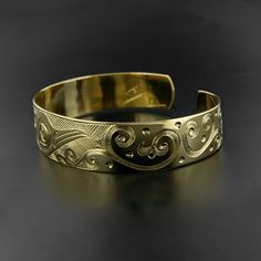 "Hand-engraved and made-to-order, this 'Hummingbird' cuff is a rare mixture of traditional Northwest Native style aesthetics and modern design. It depicts a bird in flight, with complex scrollwork representing flowers and flora. It measures 1/2\" wide by 6\" long, which will fit an average female wrist. Most wrists are between 6 1/4\"-6 3/4\" in circumference. This cuff can also be adjusted (or shaped) quite easily. It is signed by Kelvin Thompson and comes with a formal fine art appraisal, as w Artisan Gold Engraved Cuff Bracelet, Unique Gold Engraved Cuff Bracelet, Unique Gold Etched Cuff Bracelet, Unique Engraved Gold Cuff Bracelet, Artisan Gold Bracelets Engraved, Artisan Gold Bracelet Engraved, Artisan Gold Bracelet With Engraved Details, Artisan Gold Engraved Bracelets, Artisan Engraved Gold Bracelets