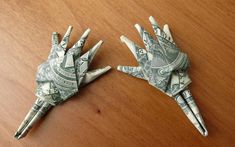 two origami hands made out of dollar bills on a table with a wooden surface