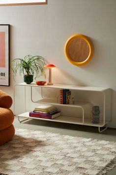 a living room with an orange chair and a white shelf