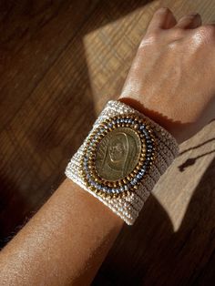 a woman's arm wearing a bracelet with a coin on it and beads around the wrist