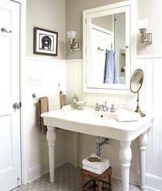 a white sink sitting under a bathroom mirror next to a wooden stool in front of a doorway