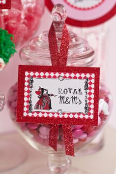 a red and white candy jar with a name tag on it that says, birthday party queen of hearts